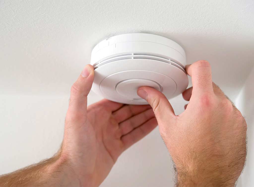 Smoke detector installer in London fitting a smoke alarm safely
